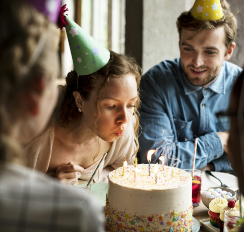 Woman Blowing Candles on Cake on Her Birthday Party Celebration