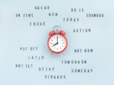 Creative top view flat lay of alarm clock with messages about delay or starting doing task copy space blue background minimal style. Concept of procrastination, time management in business and life
