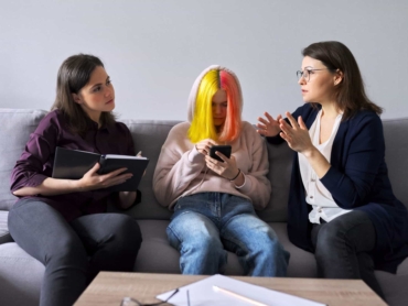 Family mother and teenage daughter in meeting with psychologist. Professional help, support, women are sitting in office on couch. Psychology, therapy, adolescence, relationship parent child teenager