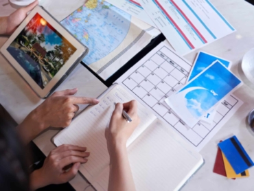 Close-up shot of unrecognizable couple taking necessary notes and planning vacation trip to Europe while sitting at table