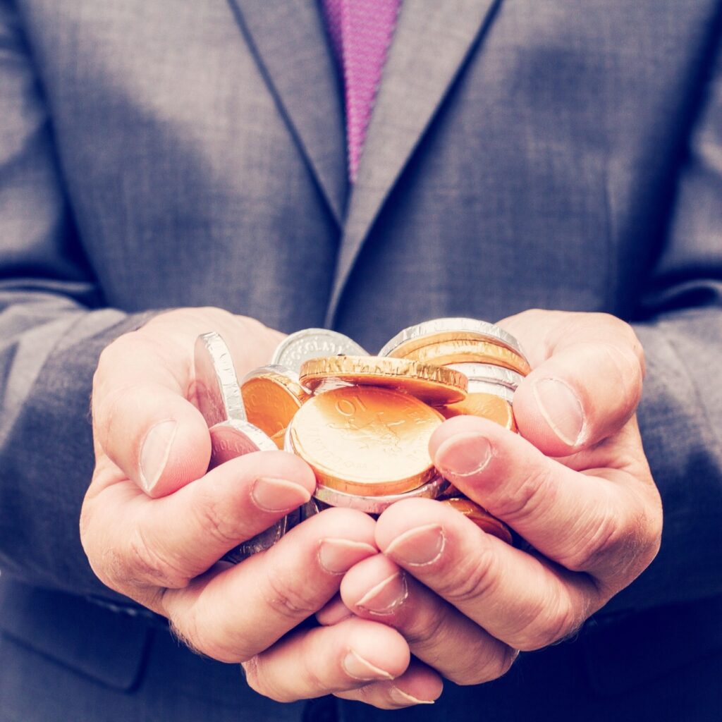 A businessman in a suit holding a handful of a gold and silver coins money or cash n hands