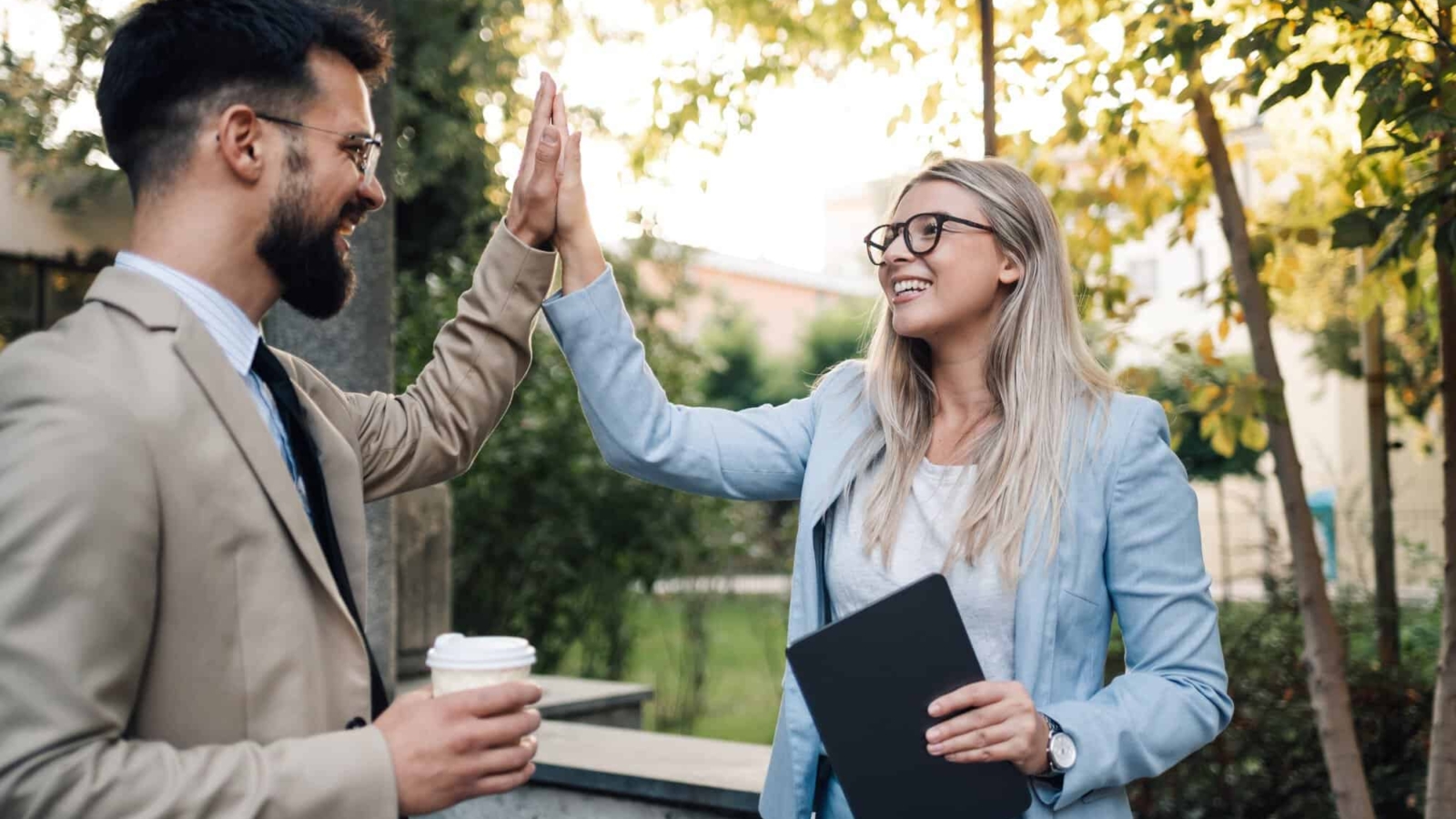 Business people giving high five outdoors after successful business deal
