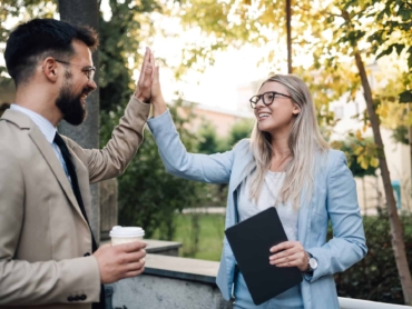 Business people giving high five outdoors after successful business deal