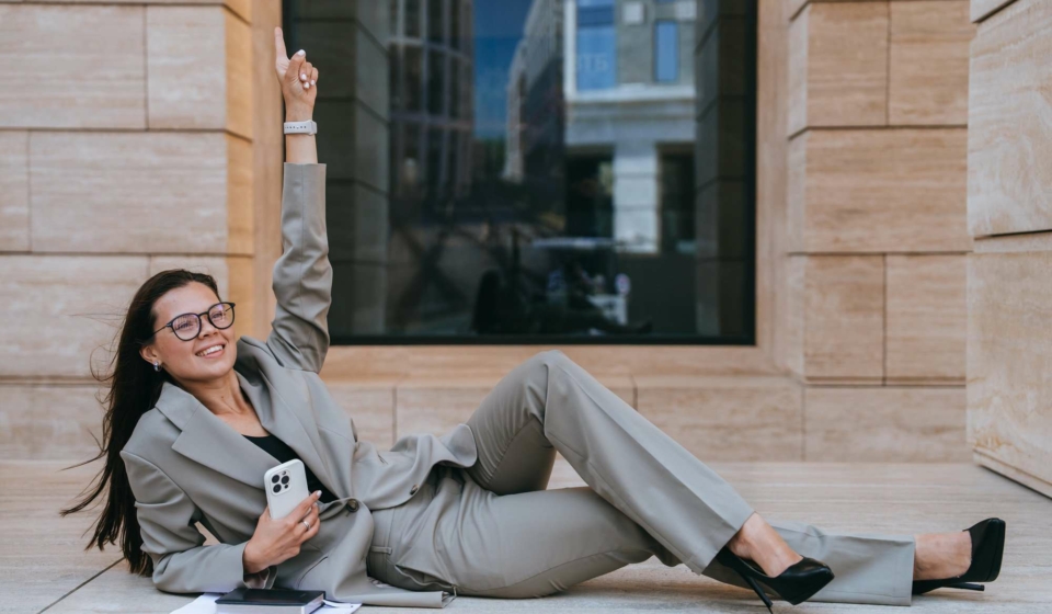 Successful businesswoman in suit laying on building balcony rising finger up celebrating success