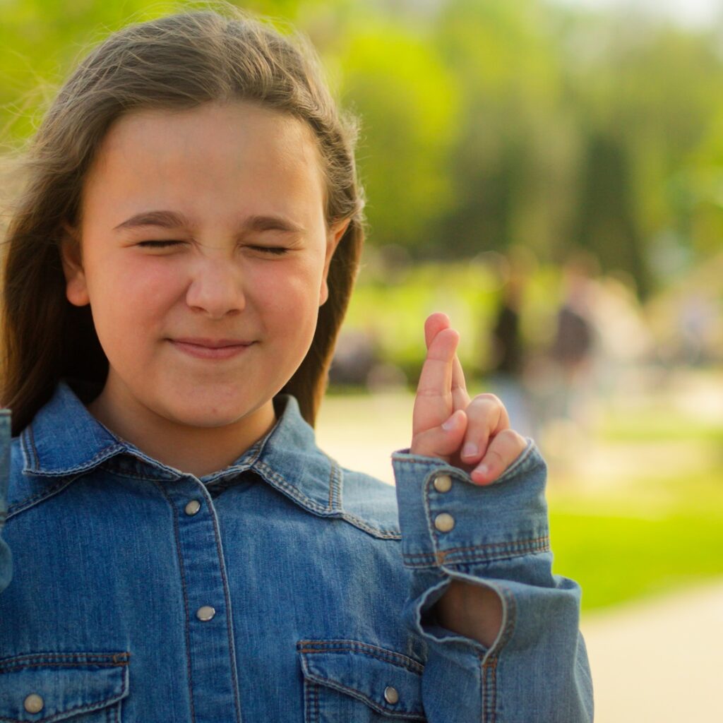 Caucasian child little girl schoolgirl crossing fingers hope adopted kid female orphan wish happy
