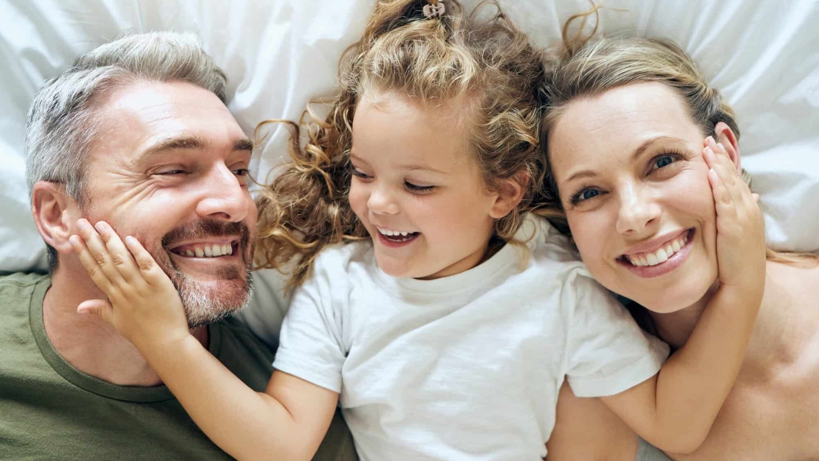 Family, happy and smile of people in bed at home feeling relax in a bedroom bonding. Mother, girl a