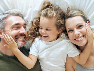 Family, happy and smile of people in bed at home feeling relax in a bedroom bonding. Mother, girl a
