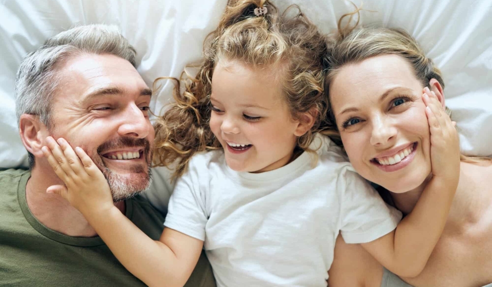 Family, happy and smile of people in bed at home feeling relax in a bedroom bonding. Mother, girl a