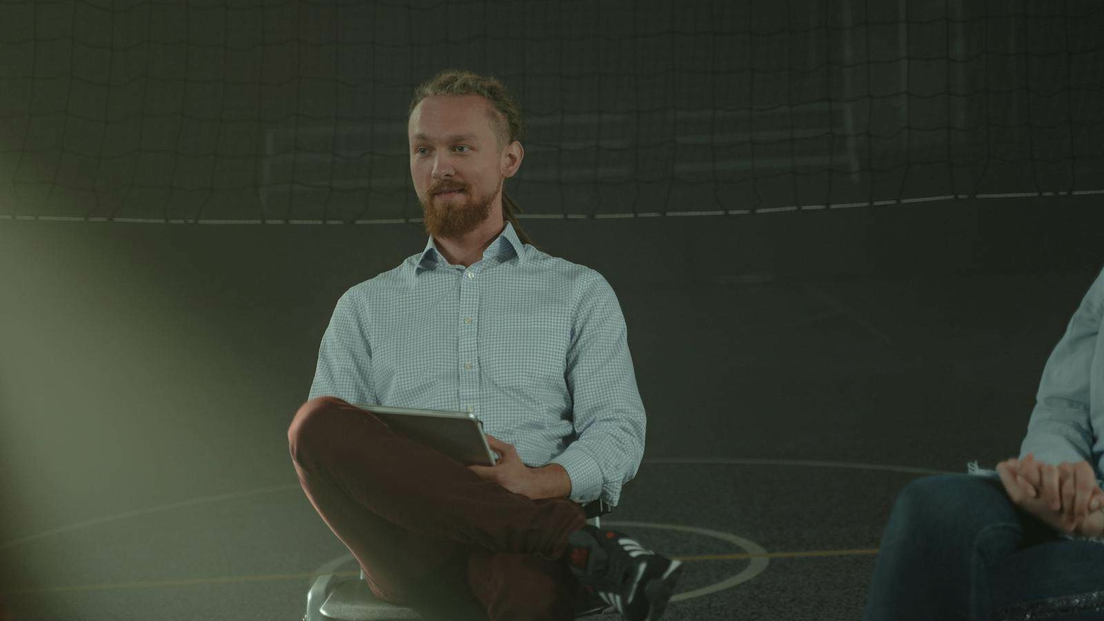 A man holds a meeting in a dimly lit room, engaging with others in a discussion.