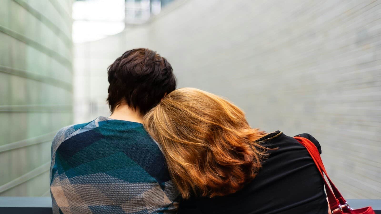 a woman rests her head on another person's shoulder