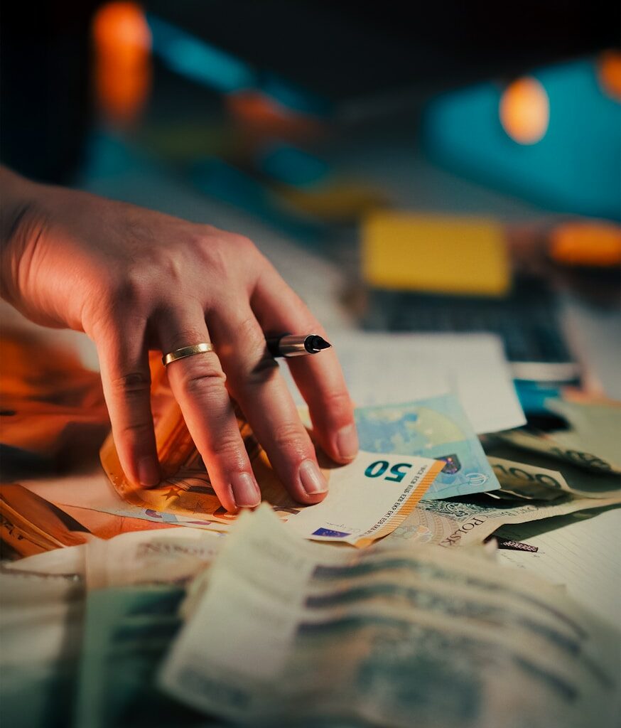 Hand reaching for a stack of euro banknotes.
